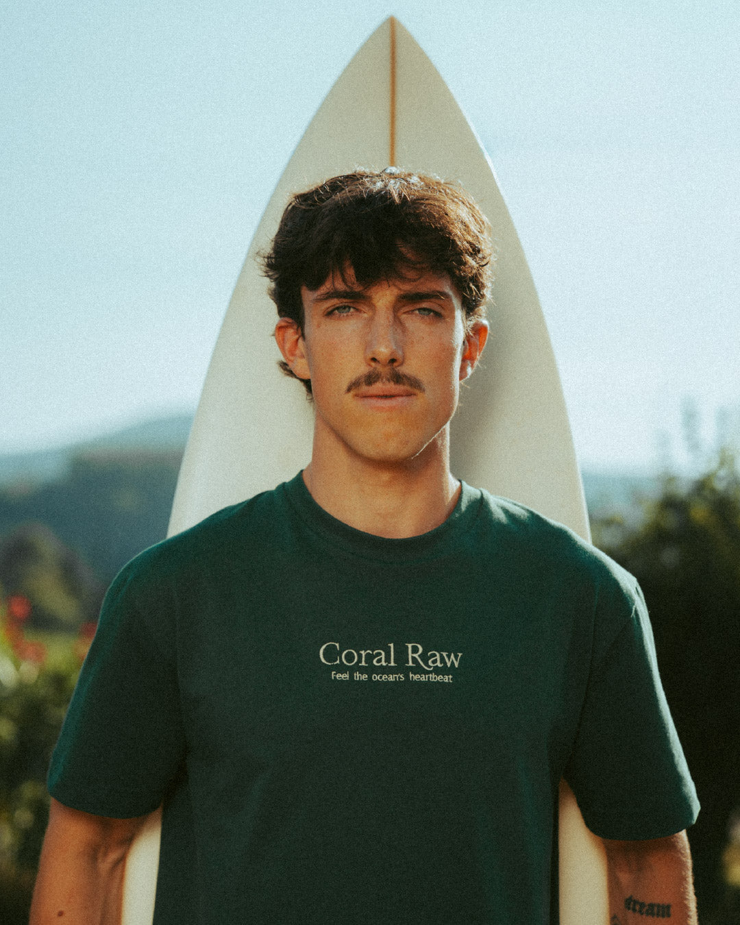 Portrait sustainable t-shirt "Feel the Ocean's Heartbeat" with an island mountain background during an outdoor photoshoot.