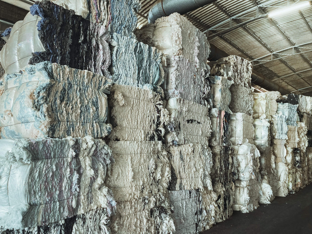 Wide view of bales of recycled cotton fibers, sourced from post-industrial textile waste for Coral Raw upcycled garments.