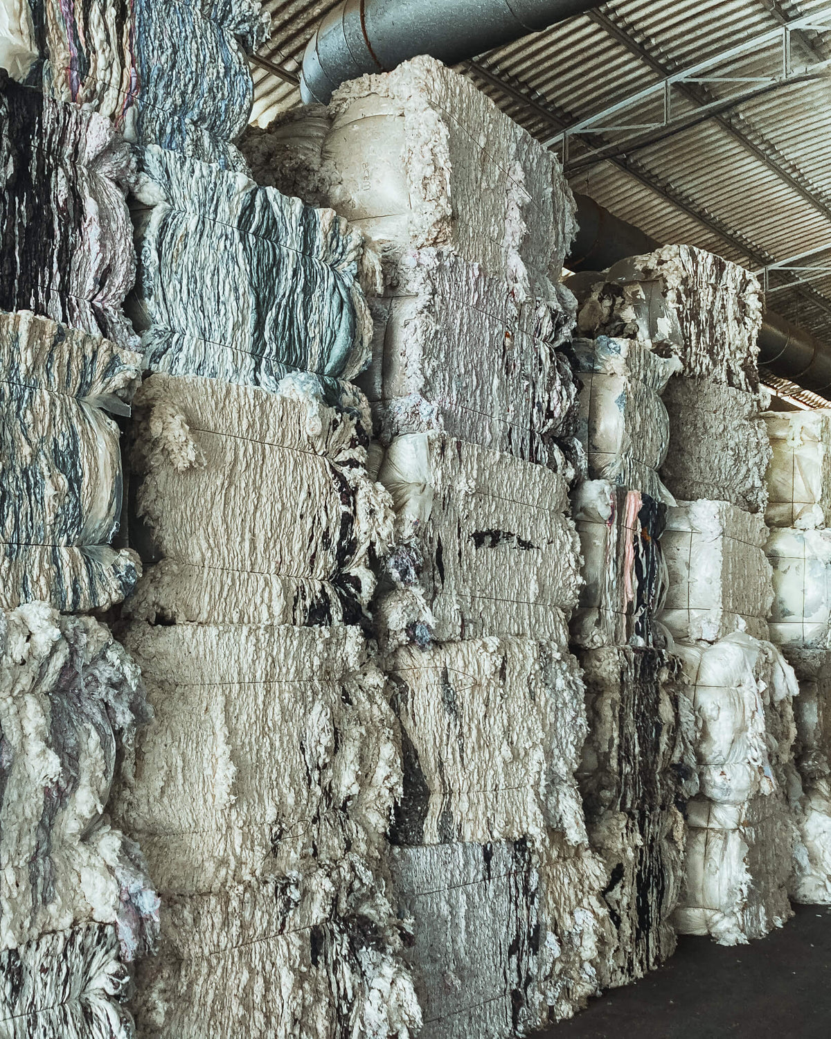 Bales of recycled cotton fibers, sourced from post-industrial textile waste for Coral Raw upcycled garments.